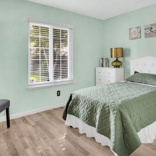 A cozy bedroom with green walls, featuring a single bed and natural light from a window with blinds.