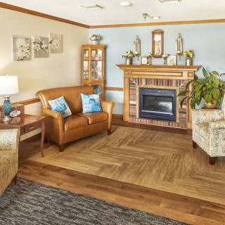A cozy living room with a fireplace, featuring brown sofas and blue decorative accents.