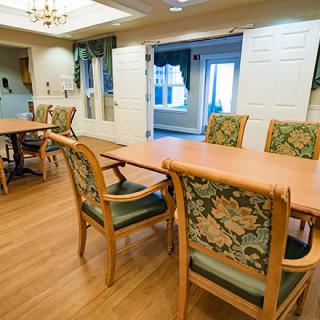A cozy dining room with wooden tables and upholstered chairs, featuring a warm interior design.