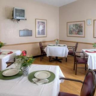 A cozy dining room with neatly set tables, decorated with plants and artwork.