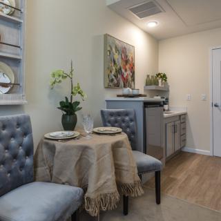 A cozy dining nook with a small round table, tufted chairs, and elegant decor.