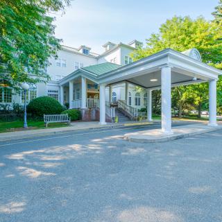 A building entrance with a covered canopy and surrounding trees.
