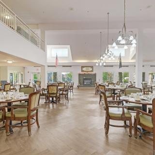 A spacious and elegant dining area with multiple tables and chairs arranged neatly, featuring stylish lighting fixtures.