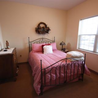 A cozy bedroom with a pink bedspread and decorative items.