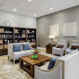 A modern living room with neutral tones, featuring comfortable seating, a wooden coffee table, and book-filled shelves.