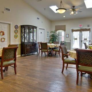A well-lit dining area with multiple tables and chairs, featuring hardwood floors and decorative elements.