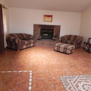 A cozy living room with a tiled floor, featuring a sofa set around a brick fireplace.