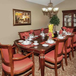 An elegantly set dining room table with matching chairs and a chandelier overhead.