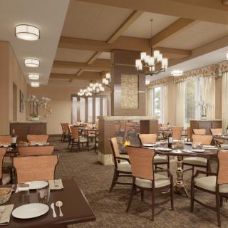 A spacious and elegantly designed restaurant dining area with neatly arranged tables and chairs, warm lighting, and tasteful decor.