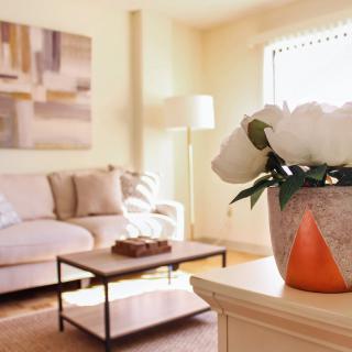 A cozy living room with a comfortable sofa, a coffee table, and a vase of flowers.
