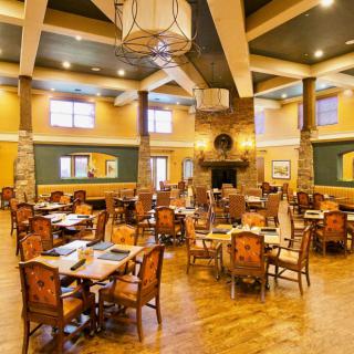 A spacious and warmly lit restaurant dining area with neatly arranged tables and chairs.