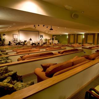 An auditorium with comfortable couch seating and a stage at the front.