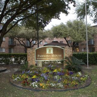 Entrance sign of a residential apartment complex surrounded by landscaping and trees.