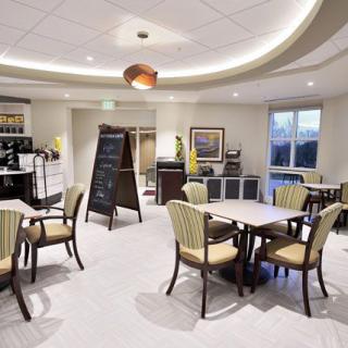 A modern cafe setting with tables, chairs, and a chalkboard menu.