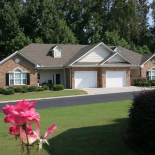 A suburban brick house with a well-maintained lawn and two garages.