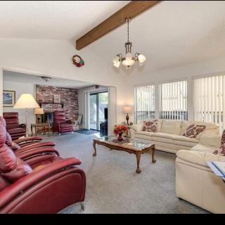 A cozy living room with red armchairs, a beige sofa, and a brick fireplace.