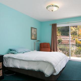 A cozy bedroom with turquoise walls and a large window letting in natural light.