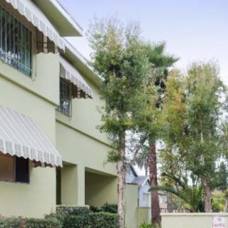 A residential building with green awnings and surrounding trees.