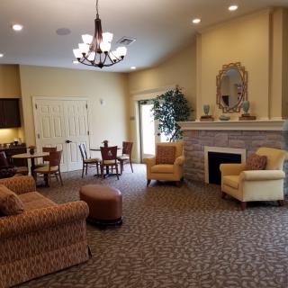A cozy living room with comfortable seating, a fireplace, and a chandelier.