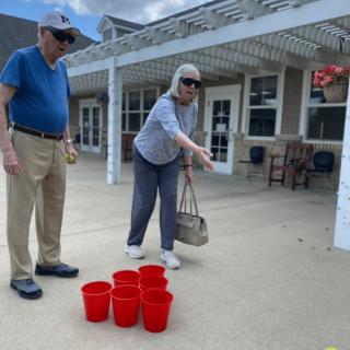An elderly couple enjoying an outdoor game with red buckets.