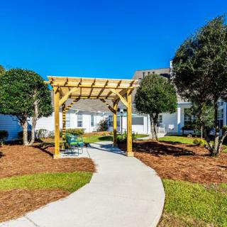 A scenic outdoor pathway with a wooden pergola and benches under a clear blue sky.