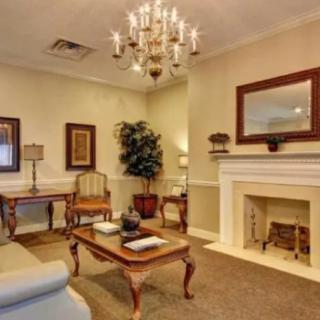 A cozy living room with a chandelier, featuring traditional furniture and a decorated fireplace.