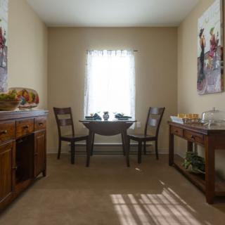 A cozy dining room with a small table and two chairs, decorated with artwork on the walls.