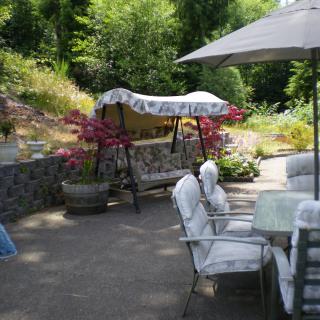 A serene garden patio with a swing, outdoor seating, and vibrant flowers.