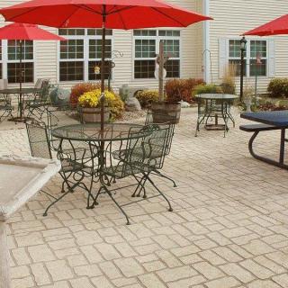 An outdoor patio area with tables and chairs under red umbrellas.