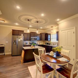 A modern kitchen with wooden flooring, pendant lighting, and a dining area.