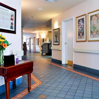 A well-lit hospital hallway featuring artwork, a flower arrangement, and inviting decor.