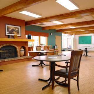 A spacious and inviting community room featuring tables and chairs, designed for gatherings and activities.