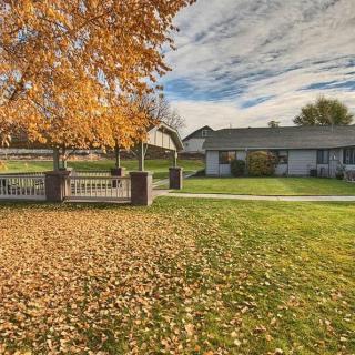 A serene autumn scene featuring a house surrounded by a grassy lawn, fallen leaves, and a tree with golden foliage.