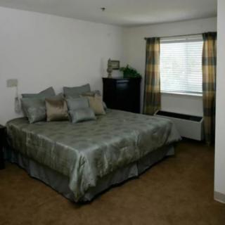 A neatly arranged bedroom with a large bed and window curtains.