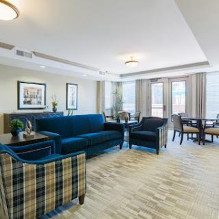 A modern and inviting living room area featuring a blue sofa, plaid chairs, and ample natural light.