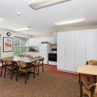 A spacious kitchen and dining area featuring tables, chairs, and modern appliances.
