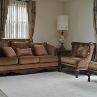A cozy living room with a brown sofa, matching armchair, and lamp.