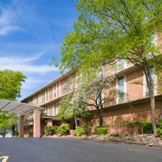 A brick hotel building surrounded by trees under a clear blue sky.