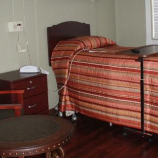 A small bedroom with a single bed, nightstand, and chair.