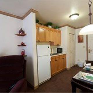 A cozy kitchen and dining area in an apartment with wooden cabinets, a fridge, and a set table.