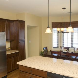 A modern kitchen with wooden cabinets and a dining area illuminated by pendant lights.