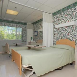 A clean and well-lit hospital room with medical beds and simple decor.