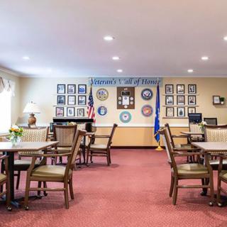 A neatly arranged dining room with tables and chairs, featuring wall decorations and an American flag.