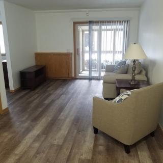 A minimalist living room with hardwood floors and simple furnishings.