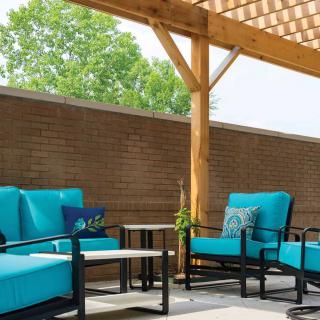 A cozy patio setup featuring blue-cushioned furniture under a wooden pergola.