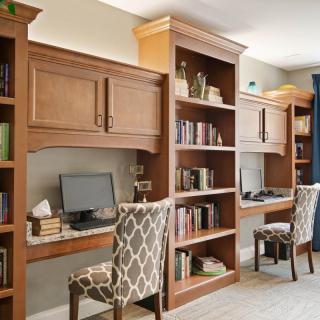 A well-organized home office with wooden desks and bookshelves.