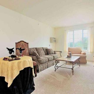 A cozy living room with a sofa, chair, and coffee table near a large window.