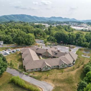 Aerial view of a large building surrounded by lush greenery and mountains.