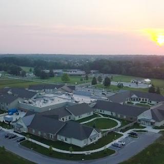 A serene aerial view of a residential facility at sunset, showcasing the layout and surrounding landscape.