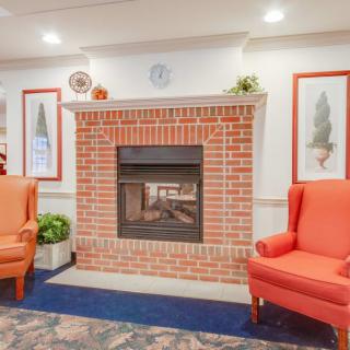 A cozy living room with a brick fireplace and orange armchairs.